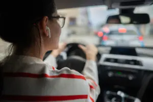 A woman wearing an airpod while driving.