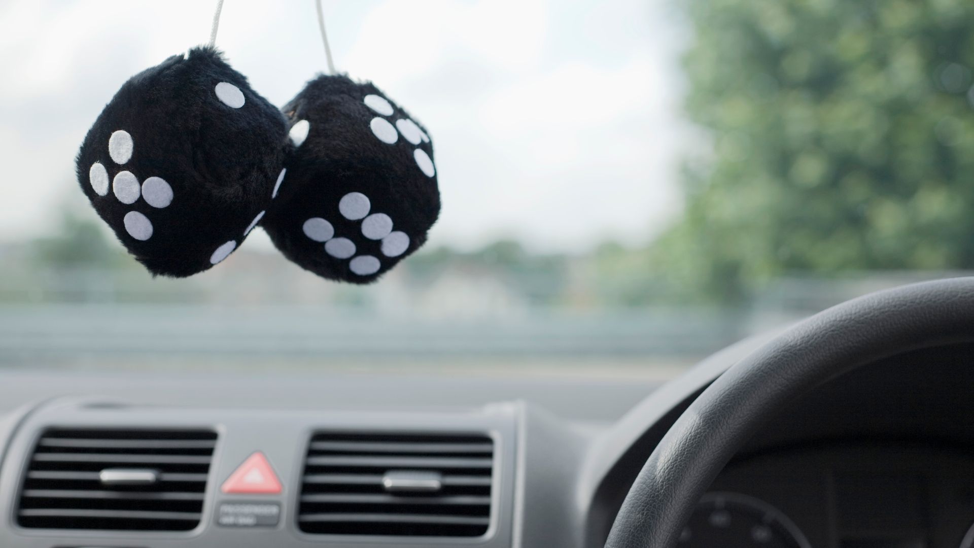 A pair of fuzzy dice hanging from a rearview mirror.