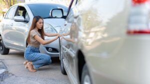 Woman inspecting the damage done to her vehicle after a car accident.