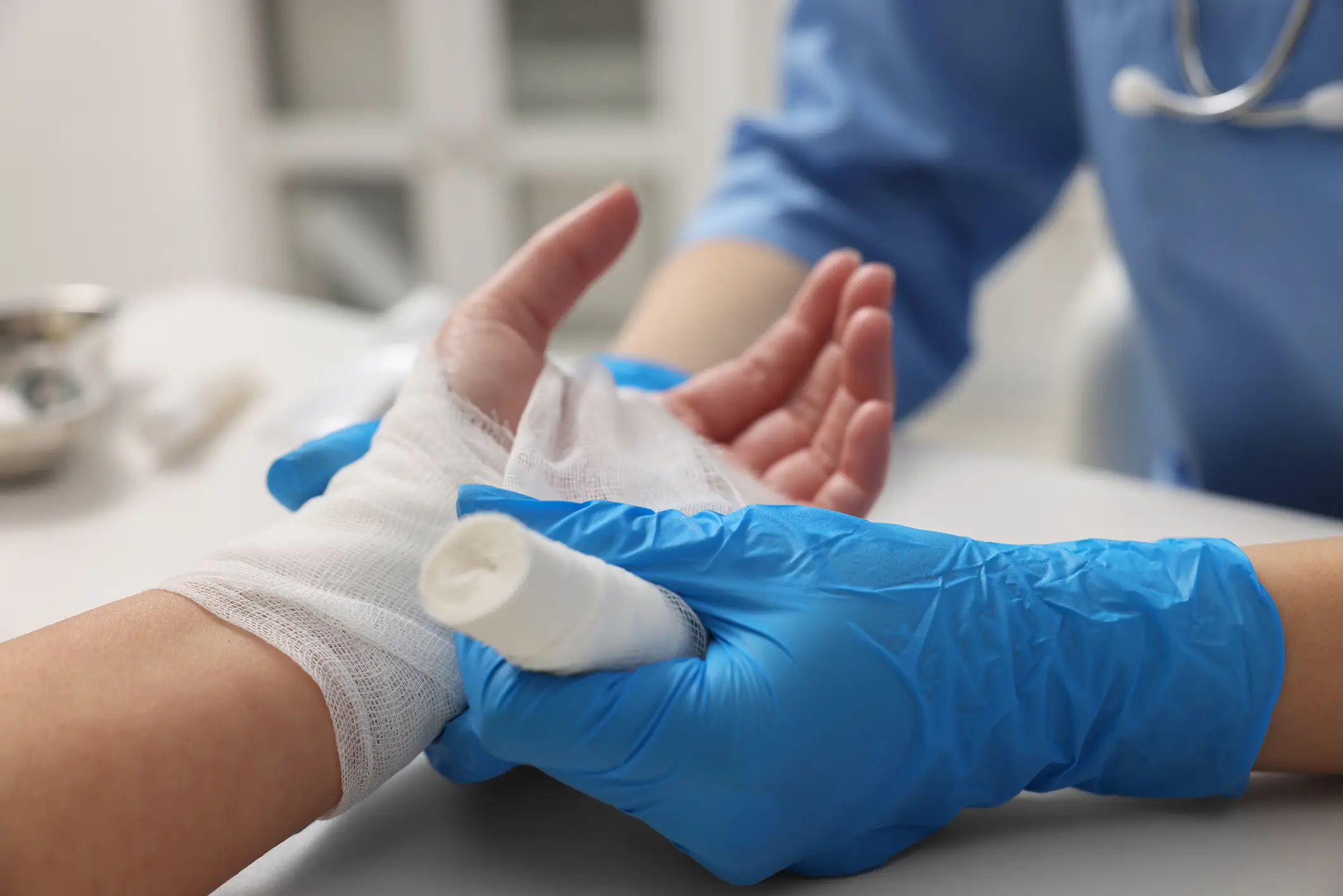 A person getting their burned hand wrapped in gauze by a doctor.