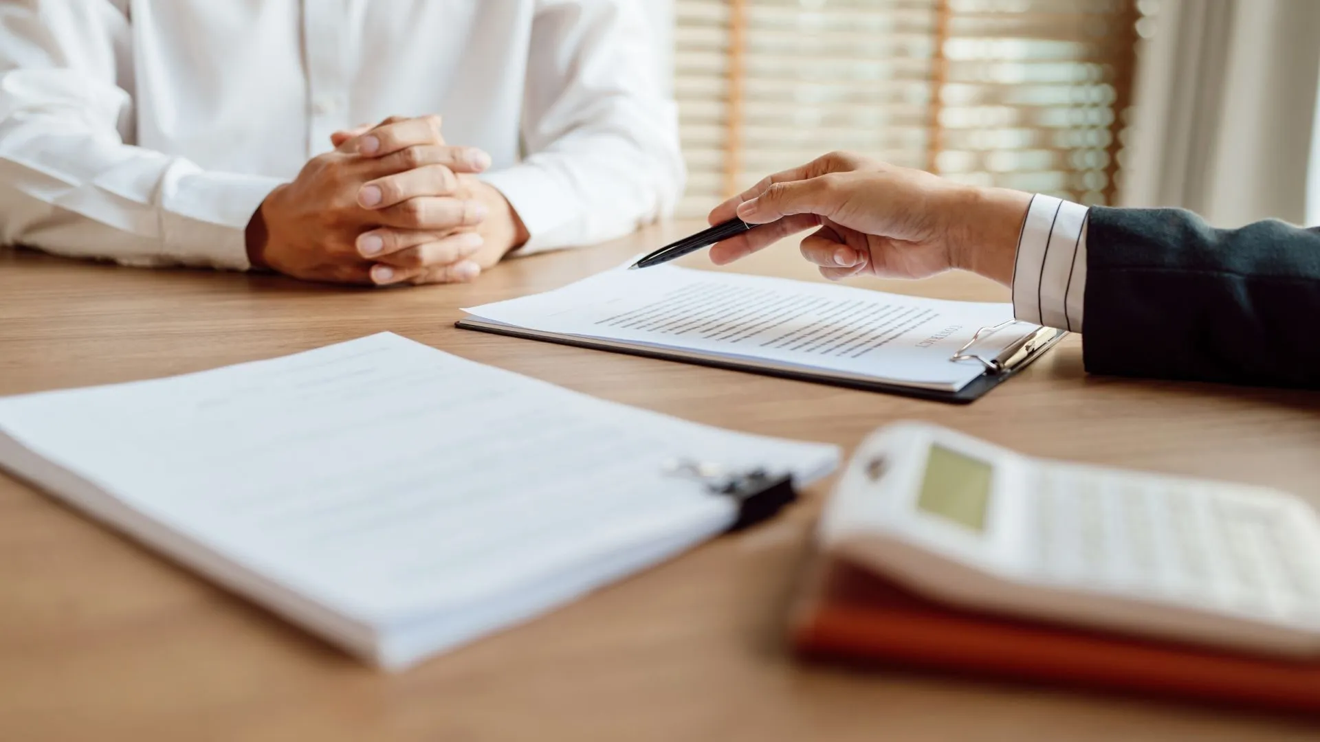 Two people in a meeting where several forms are on the table.