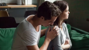 A man consoling a woman as she looks out to the distance.