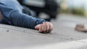 A man laying on the road, after getting hit by a car.