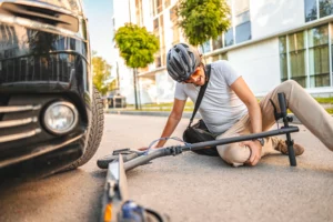 A man riding an electric scooter, getting into an accident with a car.