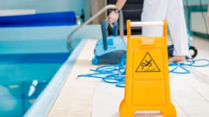A wet floor sign by a swimming pool.