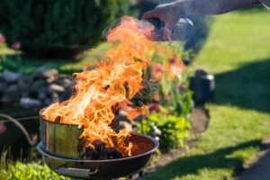 A person pouring lighter fluid on a bbq, and a big burst of flames jumps out.