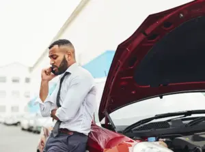 A man in a suit on the phone when his car is not running.