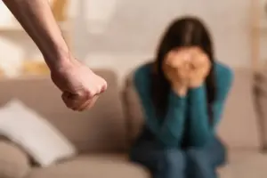 A man with a clenched fist, approaching a scared woman.