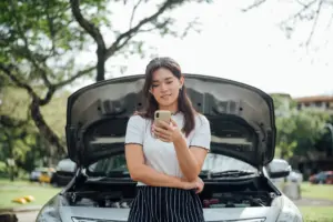 A woman on the phone after her car stopped in the middle of the road.