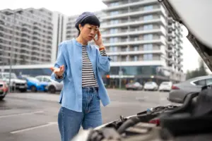 A woman arguing on the phone in front of her defective car.