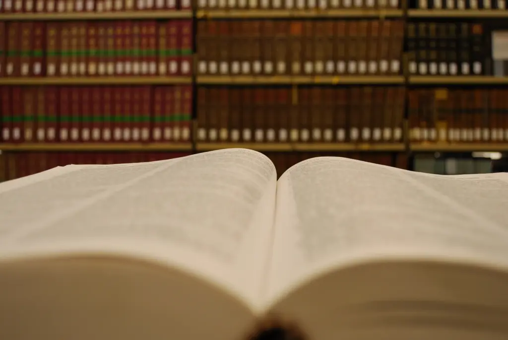 An open legal book with a bookshelf in the background.