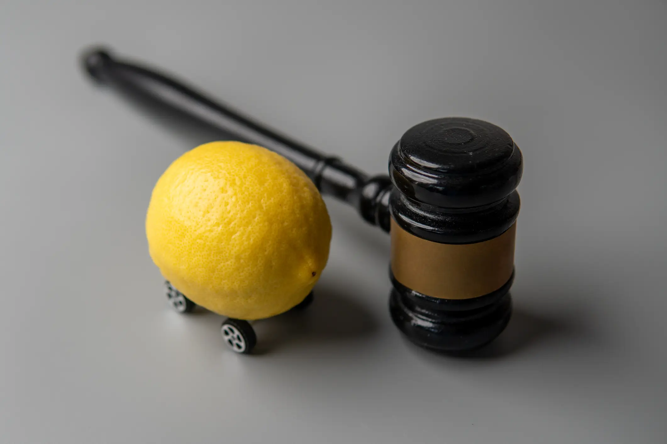 A lemon with wheels placed next to a gavel.