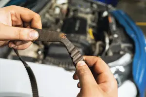 A person checking a torn strip inside a car engine.