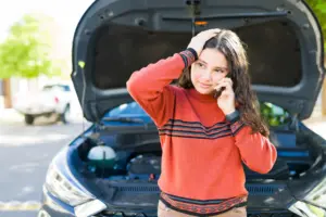 A woman on the phone after her car breaks down.
