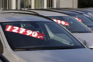 A row of used cars with a reduced sticker price on them.
