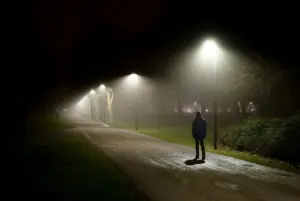 A creepy man standing in a middle of a dark park.