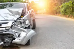 A gray car with a busted front bumper due to a speeding accident.
