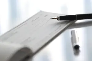 A closeup of a blank check with a pen on top of it.
