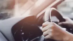 A person with their hands on the steering wheel.