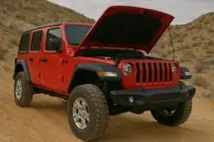 A red Jeep Wrangler with its hood and its suspension loose.