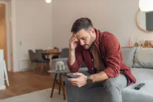 A stressed man looking on his phone.