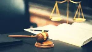 A gavel, scale, and book on a table.