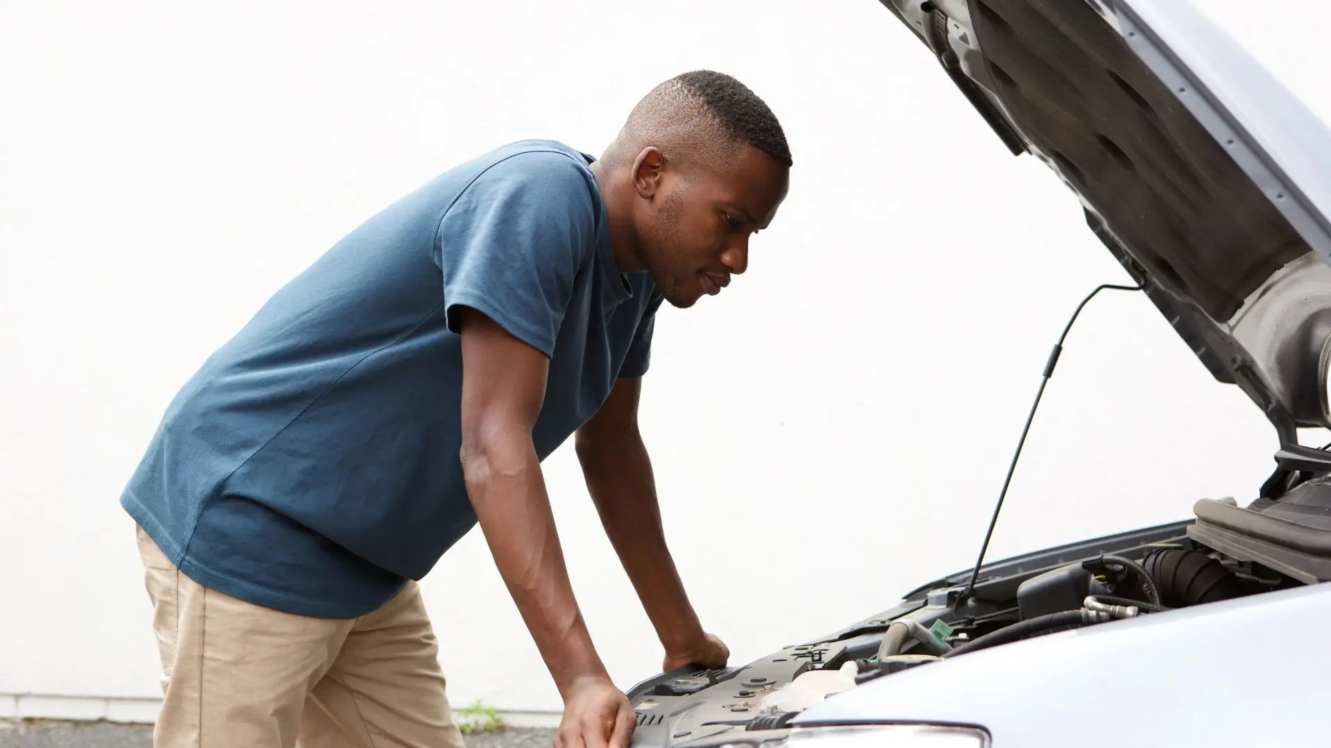 A man looking at his car engine, confused.