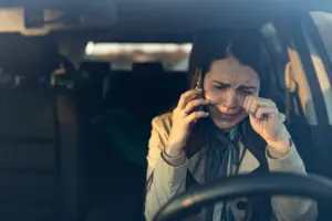 A woman crying on the phone while in the car.