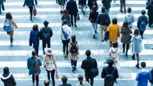 A crowd of people walking on a crosswalk. 