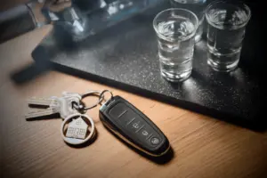 A set of car keys next to several tequila shots. 