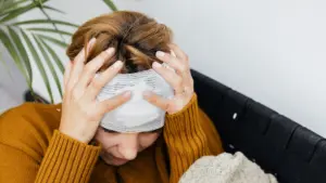 A woman holding her bandaged head. 