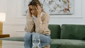 A distraught woman looking stressed while on the couch.