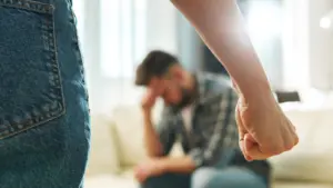 A man looking stressed while another person is making a fist towards them.