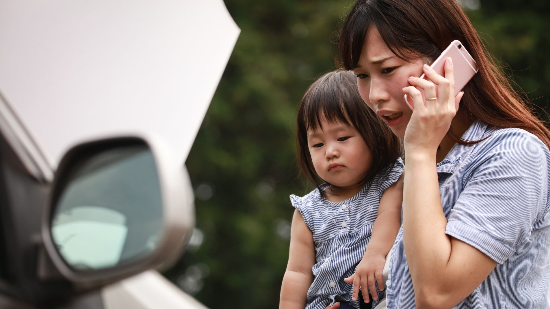 A concerned mother on the phone while holding her kid.