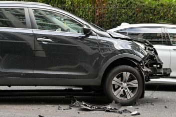 Damage to car after colliding with a traffic light London, England - June 2022: Car with extensive damage to its front after colliding wityh a traffic light. The traffic light is wedged under the vehicle.
